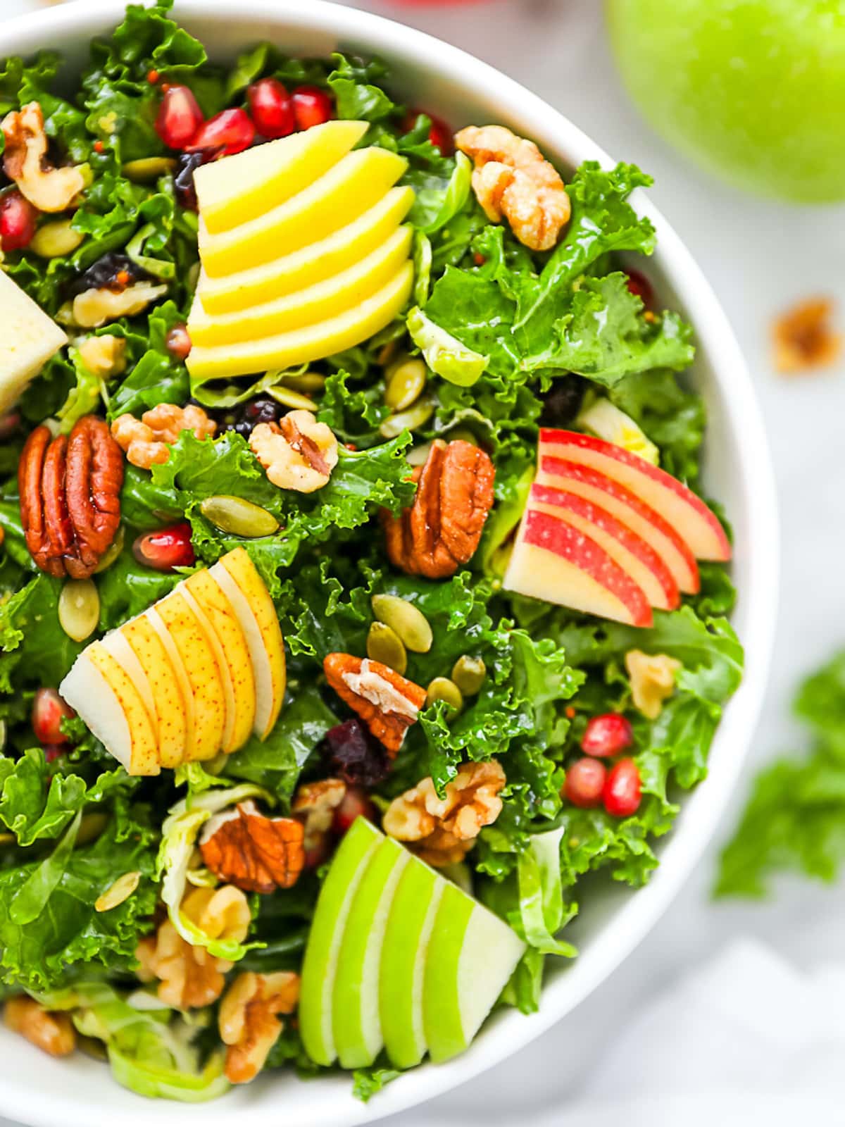 A large kale salad with apples, pears, walnuts, pecans, pomegranate seeds.