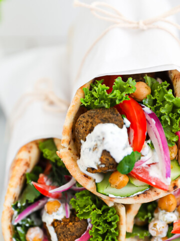 Three vegetable gyros stacked on top of each other and wrapped in white parchment paper.