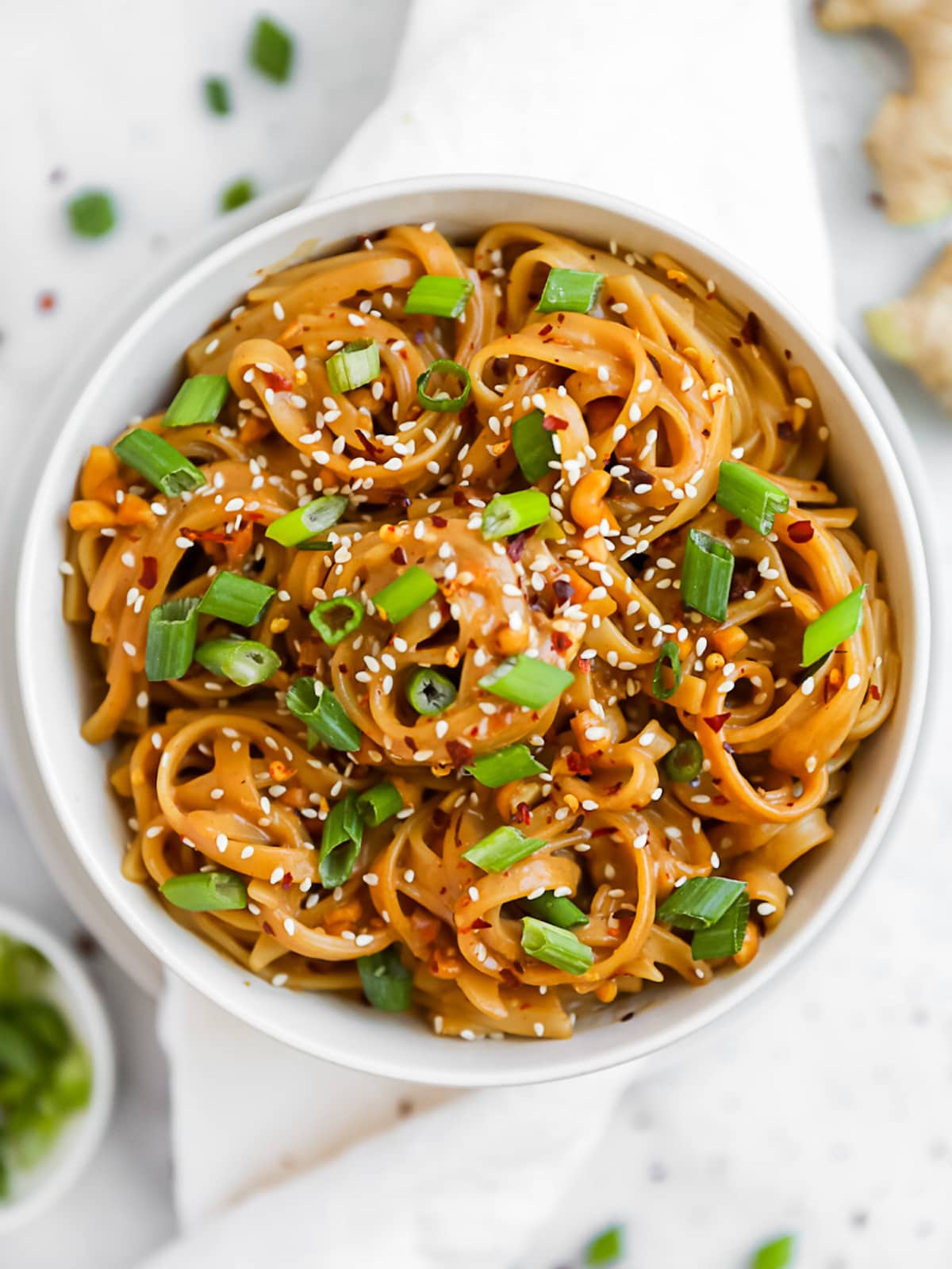 Creamy peanut noodles in a white bowl.