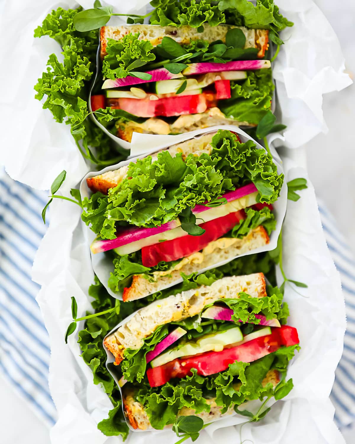 Three sandwich halves, each wrapped in white parchment paper.
