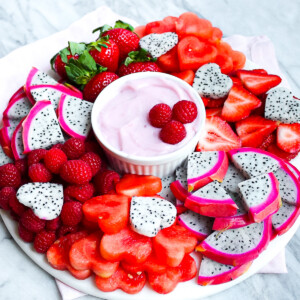A fruit platter with fresh berries, melon, and dragon fruit with a homemade fruit dip in the center.