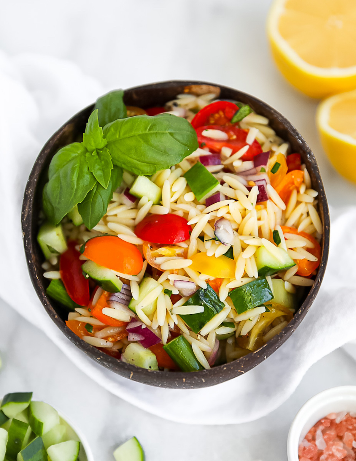 A coconut bowl filled with fresh orzo pasta salad