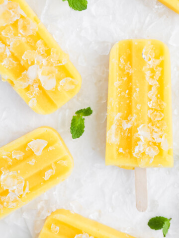 An overhead picture of yellow/orange mango popsicles. They are covered in crushed ice