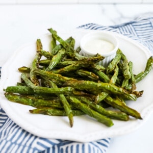 A plate filled with bright green beans that look crispy.