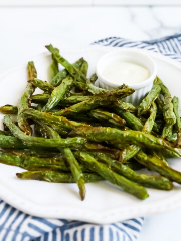 A plate filled with bright green beans that look crispy.