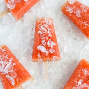 Five bright pink popsicles covered in crushed ice