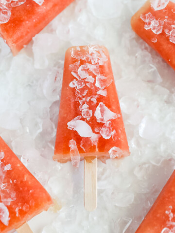 Five bright pink popsicles covered in crushed ice