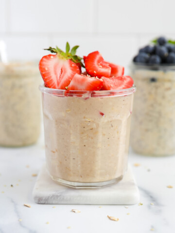 Three jars of overnight oats with berries on top of them