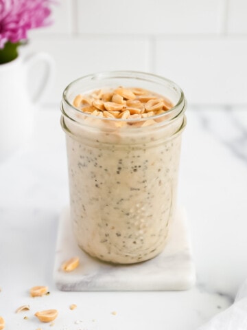 A jar filled with chia seeds and overnight oats with peanuts on top