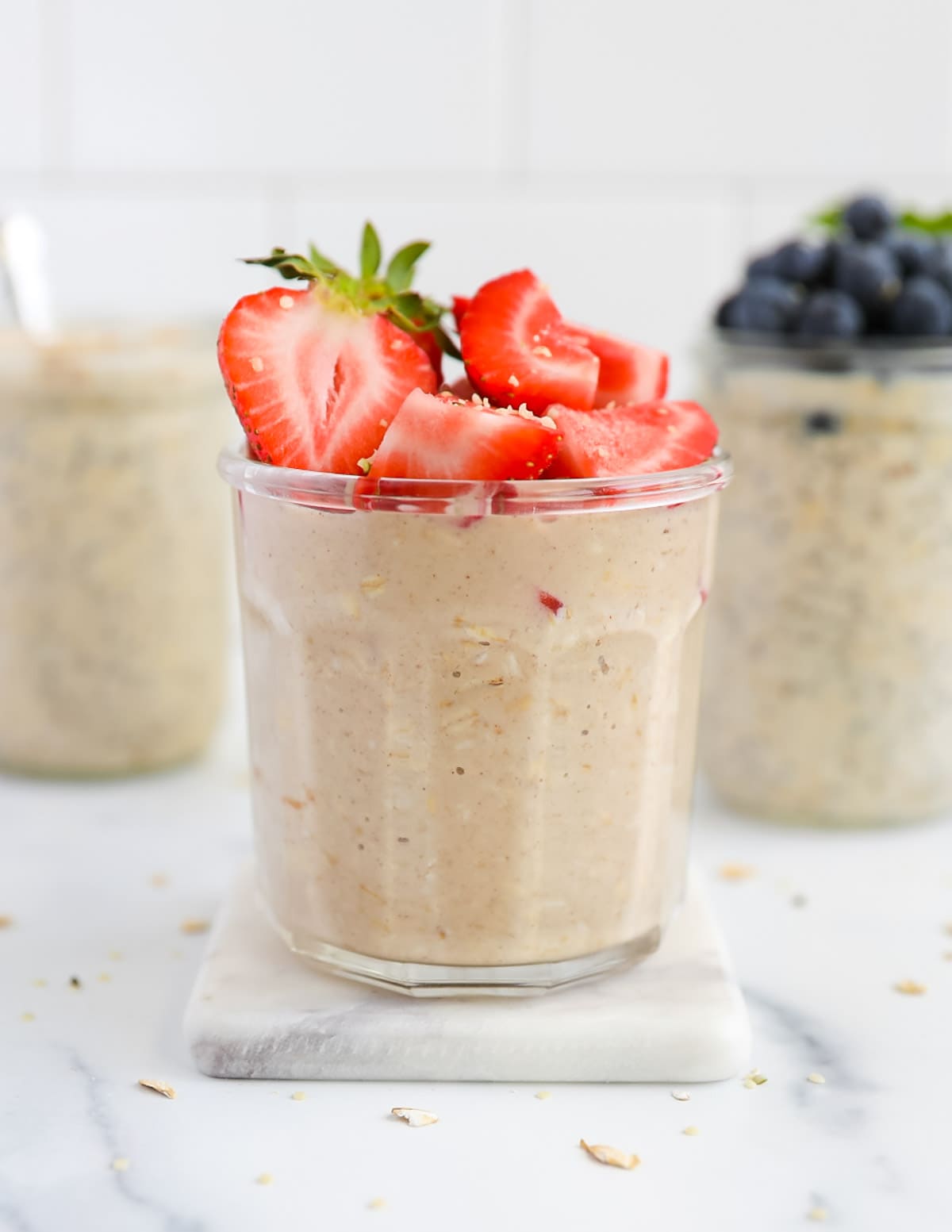 Three jars of overnight oats with fresh strawberries and blueberries on top