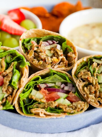 Four sliced veggie wraps with lentils and fresh vegetables in a blue dish