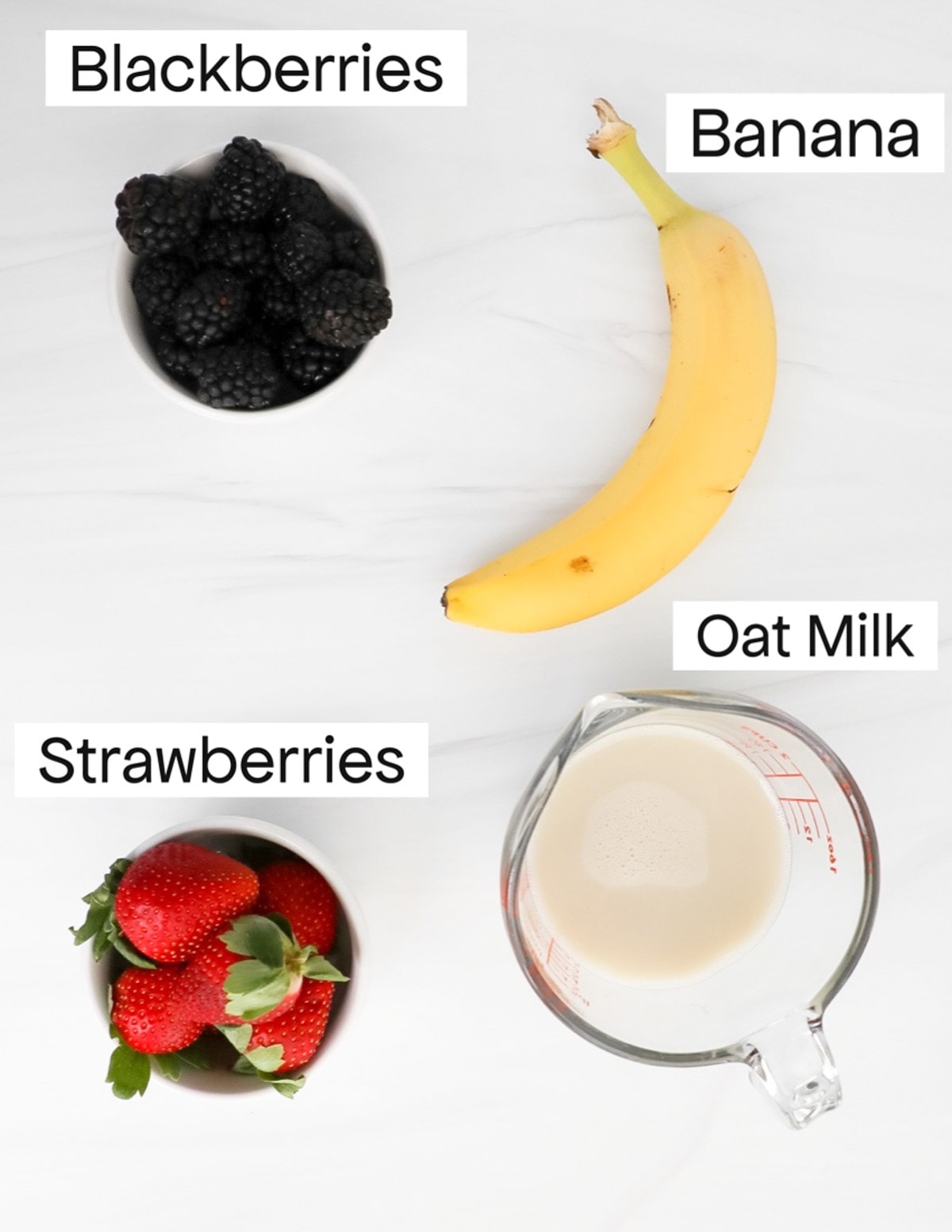 Labeled ingredients including blackberries, a banana, strawberries, and a measuring cup filled with oat milk.