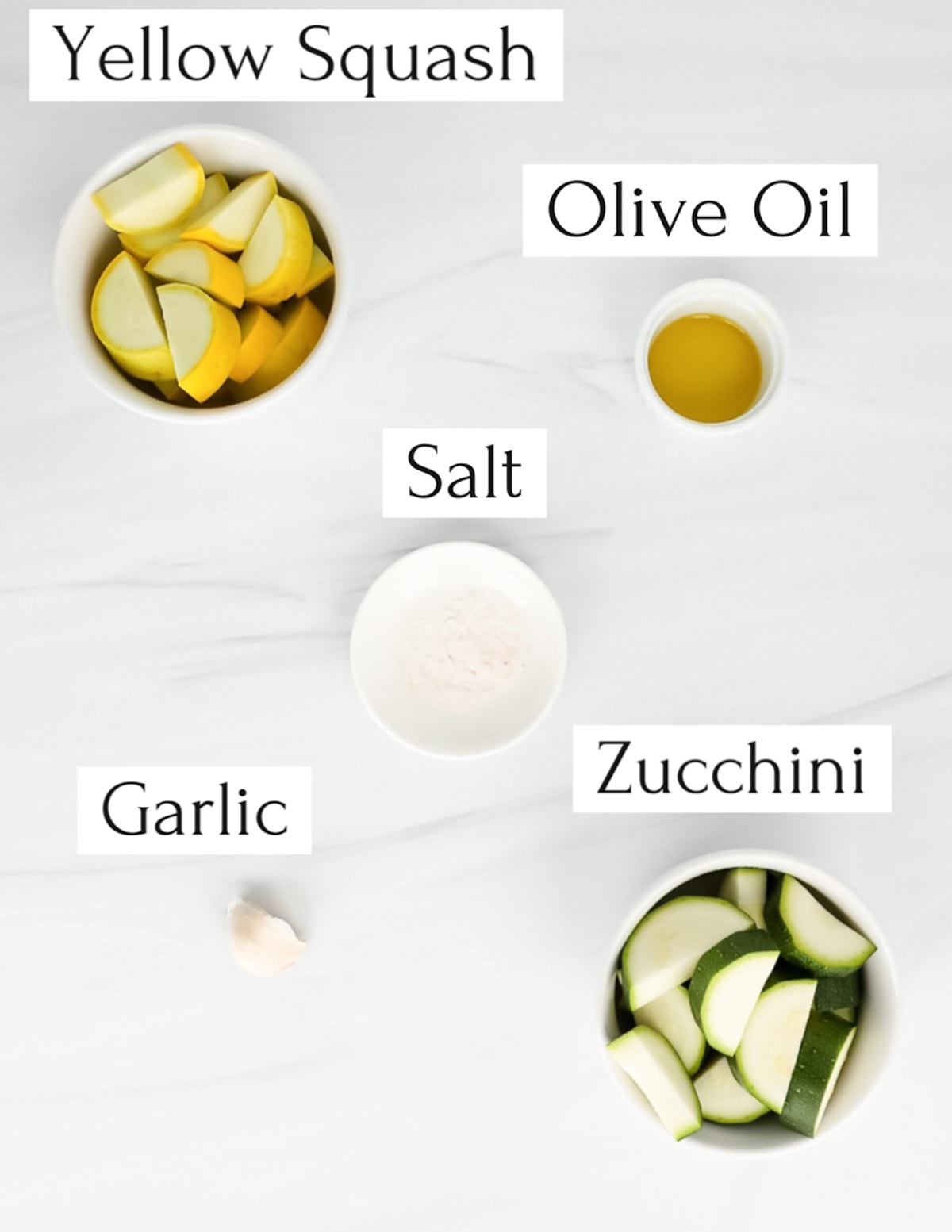 Labeled ingredients in small white bowls including: yellow squash, olive oil, salt, garlic, zucchini.