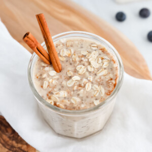 A jar of overnight oats and cinnamon sticks in the oats.