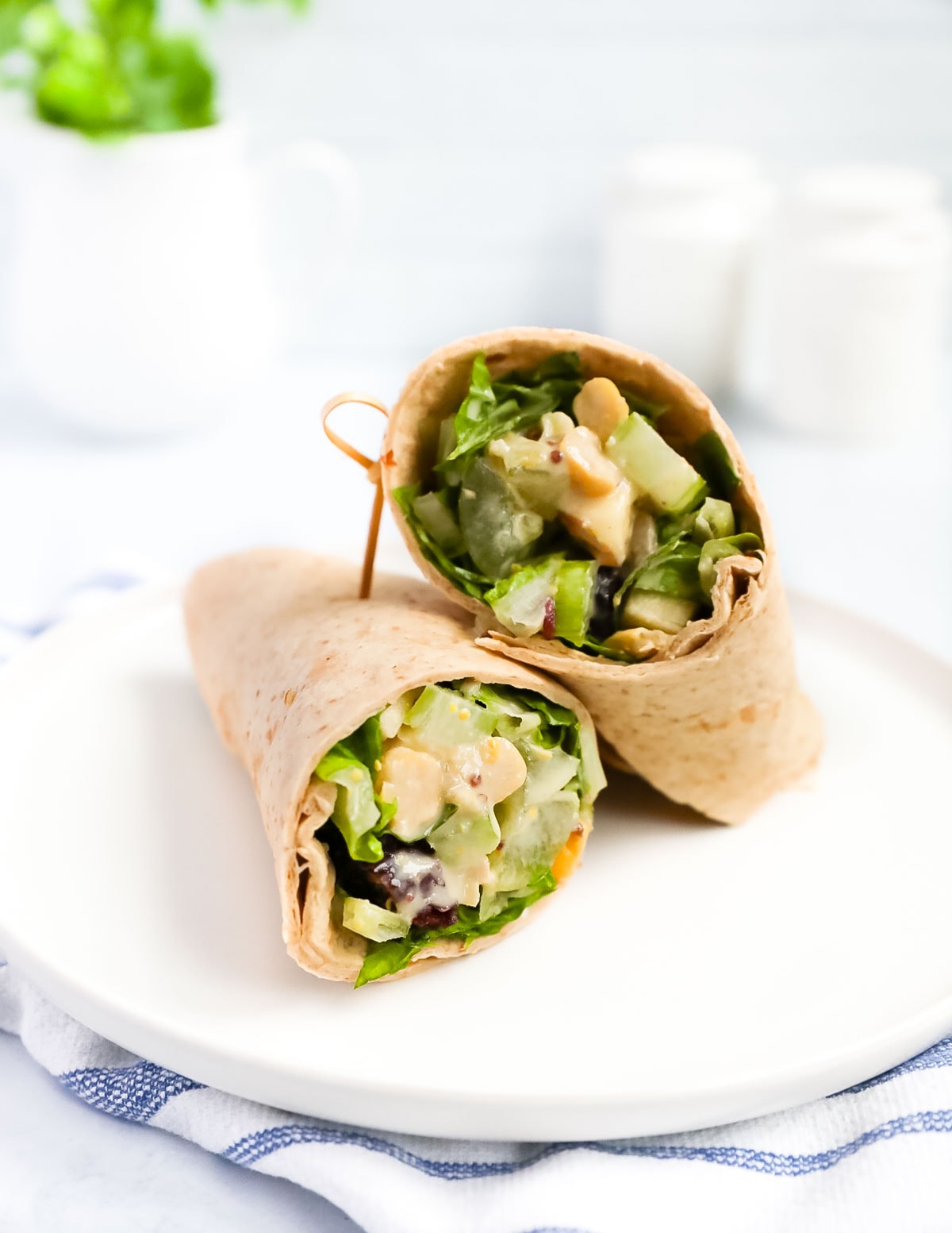 A wrap with fresh vegetables inside it on a white plate.