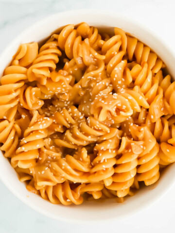 A white bowl filled with spiral pasta tossed in a creamy sauce.