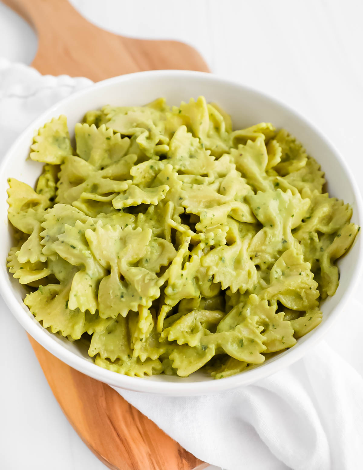 A bowl of bowtie pasta covered in a green cream sauce.
