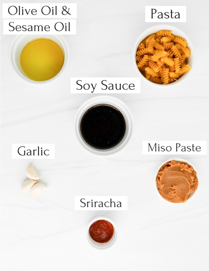 Labeled ingredients in white bowls including: olive oil and sesame oil, pasta, soy sauce, garlic, miso paste, sriracha.