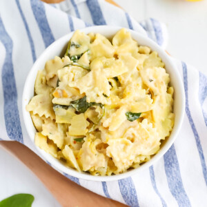 Creamy white sauce pasta with spinach in a white bowl.