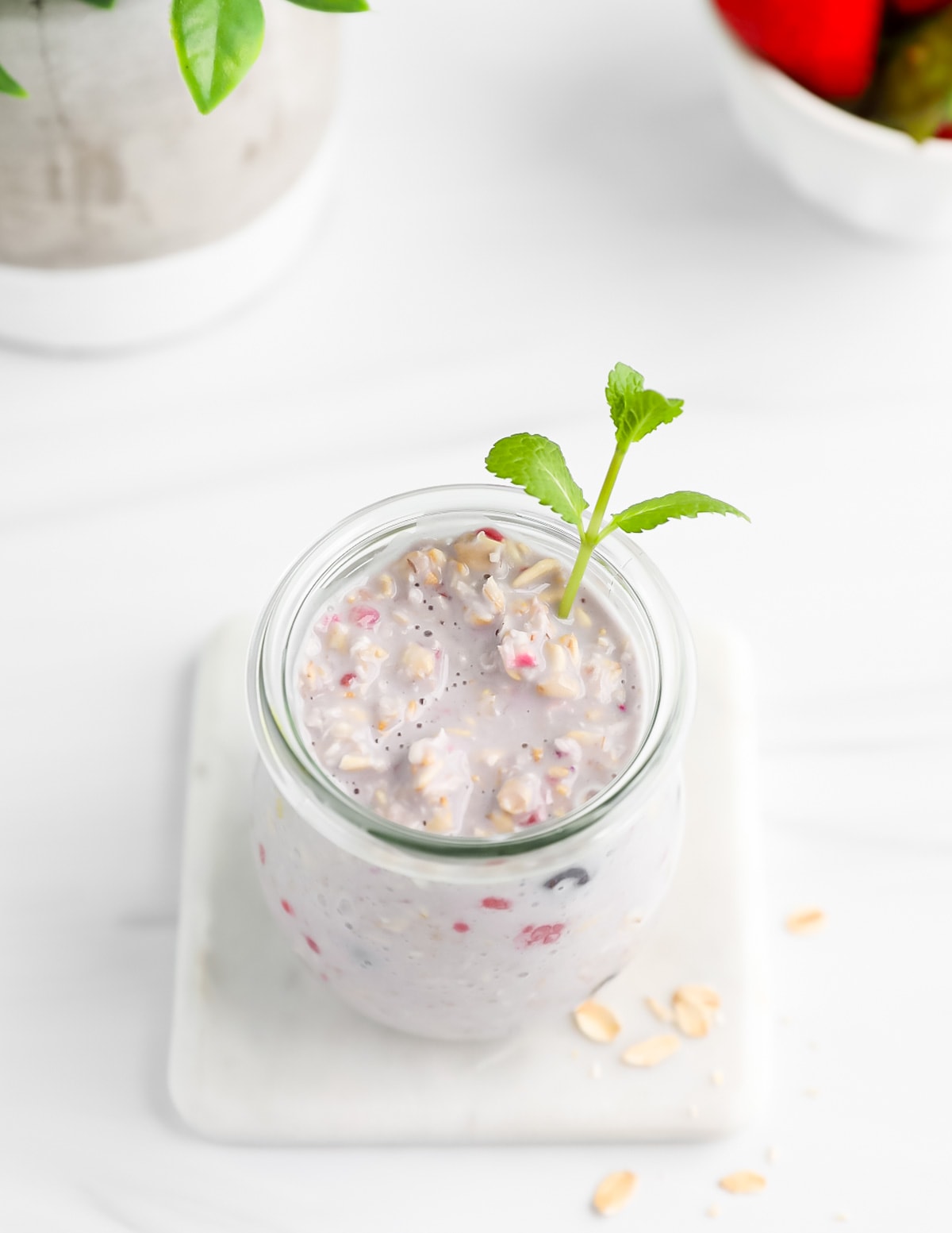 An overhead image of a jar filled with overnight oats and a sprig of fresh mint.