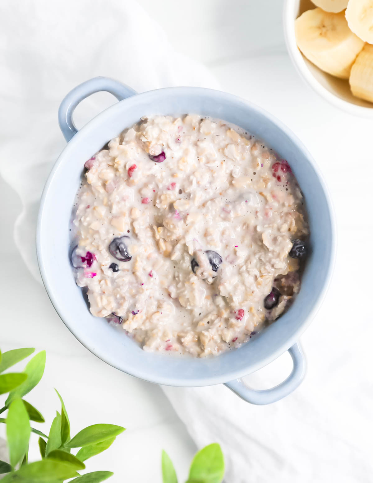 An overhead image of a blue bowl that is filled with creamy oats and frozen berries.