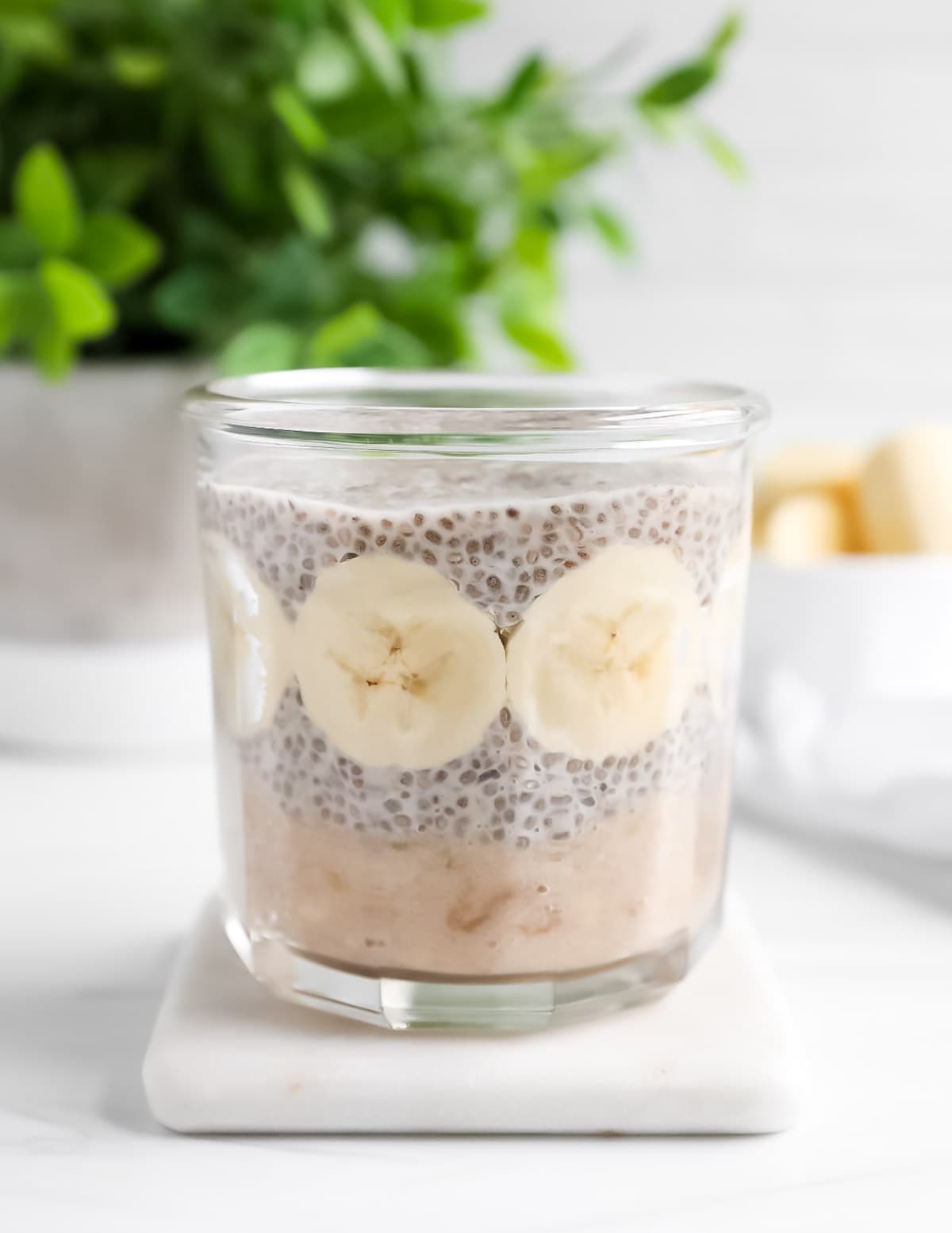 A clear glass jar filled with bananas and chia seed pudding.