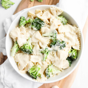 A white bowl filled with creamy bowtie pasta with broccoli in it.