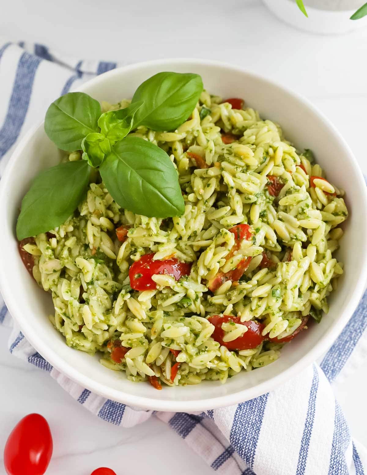 Creamy pesto orzo in a bowl garnished with basil leaves.
