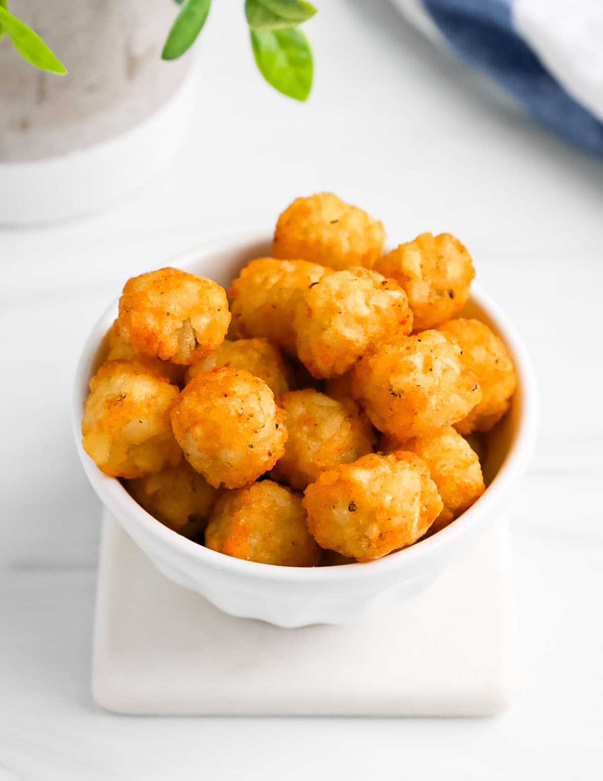 A small white dish filled with crispy tater tots.