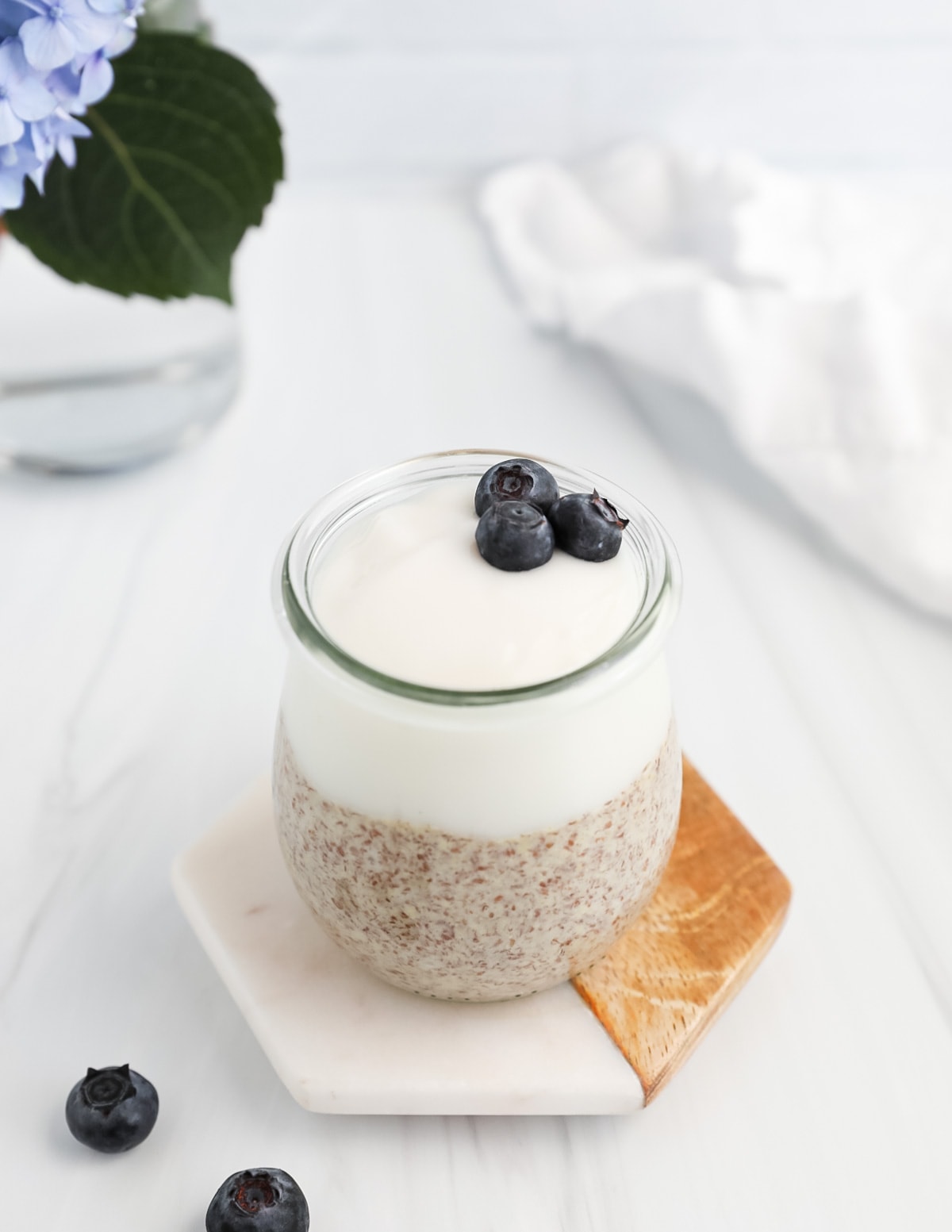 A small jar filled with flax pudding and yogurt with blueberries on top.