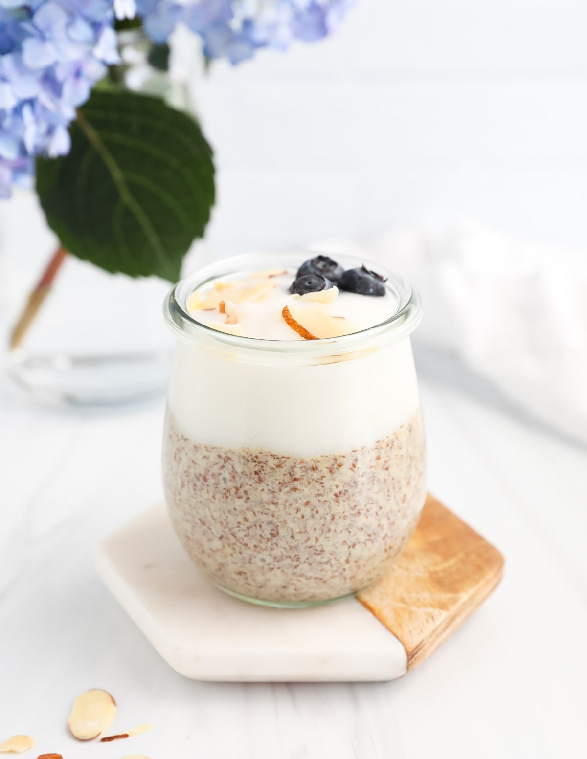 Flax pudding and yogurt in a jar with blueberries and shaved almonds on top.
