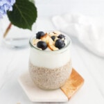 A jar filled with half flaxseed pudding and half vanilla yogurt. There are blueberries and shaved almonds on top.