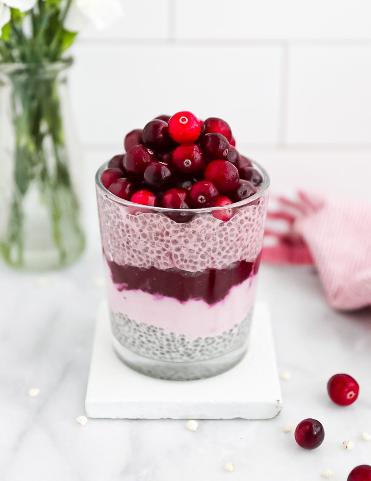 A chia parfait with layers of chia pudding, pink yogurt, cranberry sauce, and cranberries.