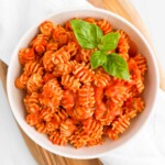 Pasta with red sauce and fresh green basil on top.