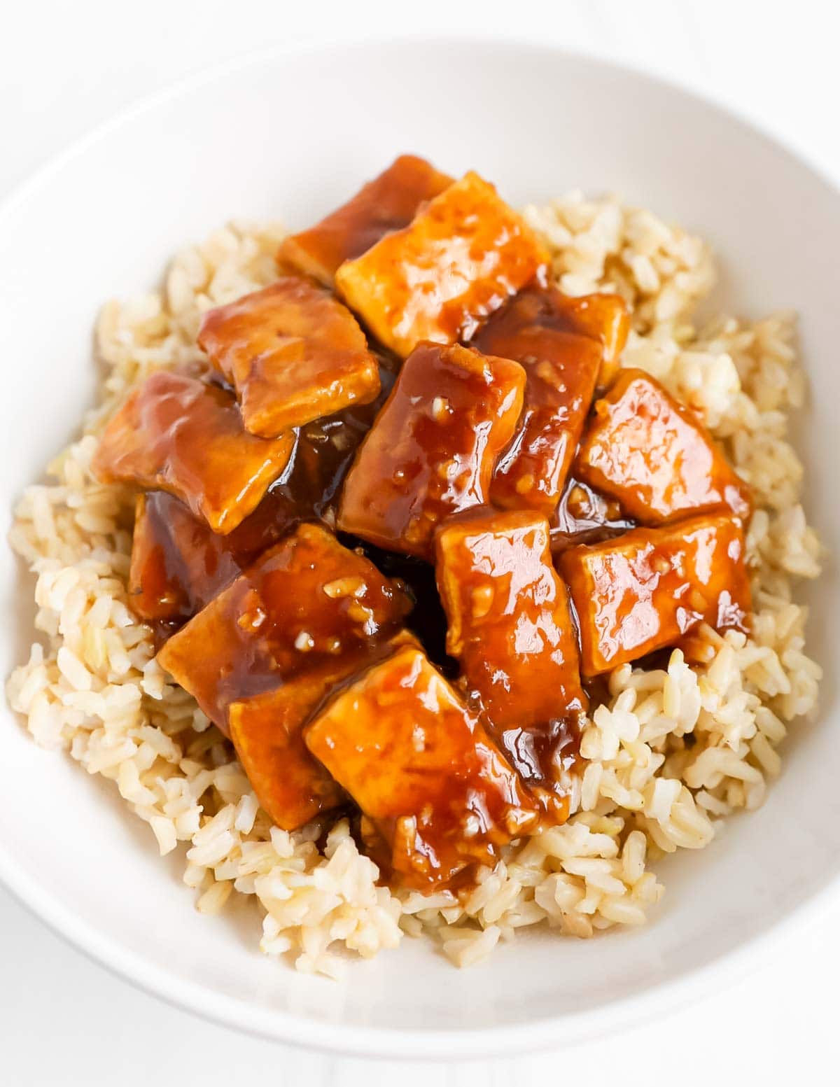 Cooked tofu over a bed of rice. The tofu is covered in a thick brown sesame sauce.