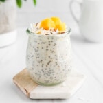 Overnight oatmeal in a jar with nuts, coconut flakes, and mango on top.