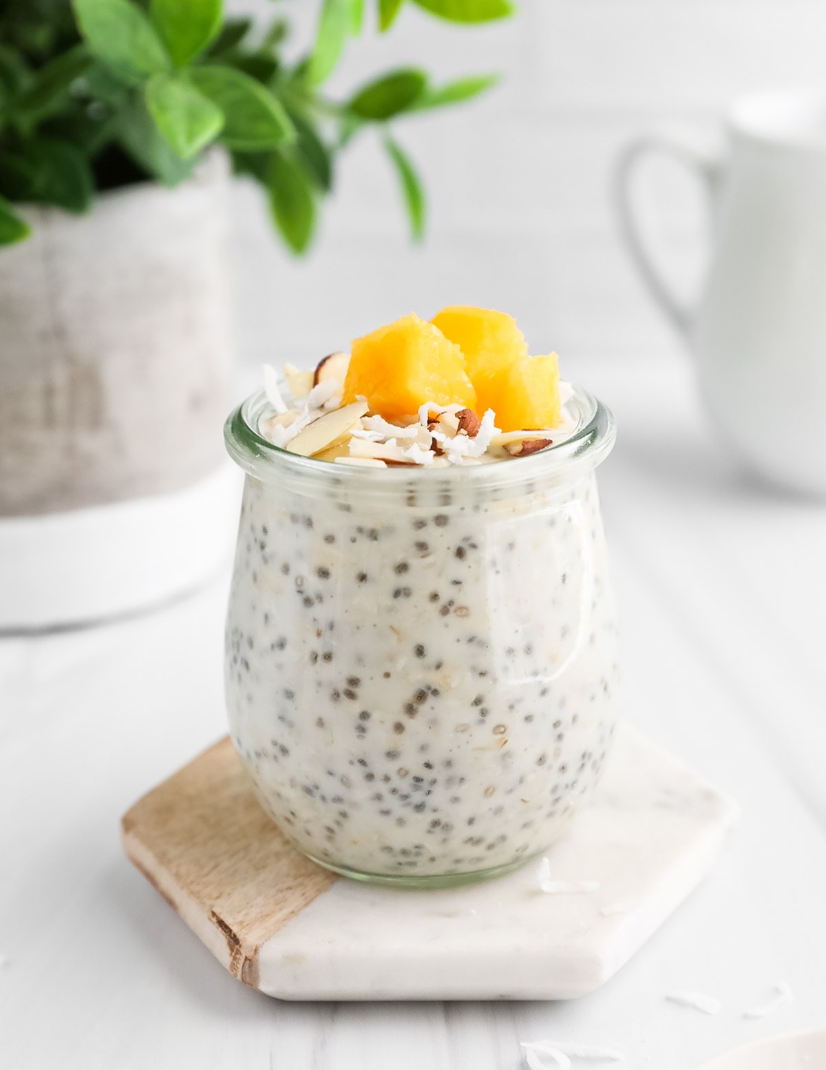 Chia seeds and oats in a jar with mango, shaved almonds, and coconut flakes on top.