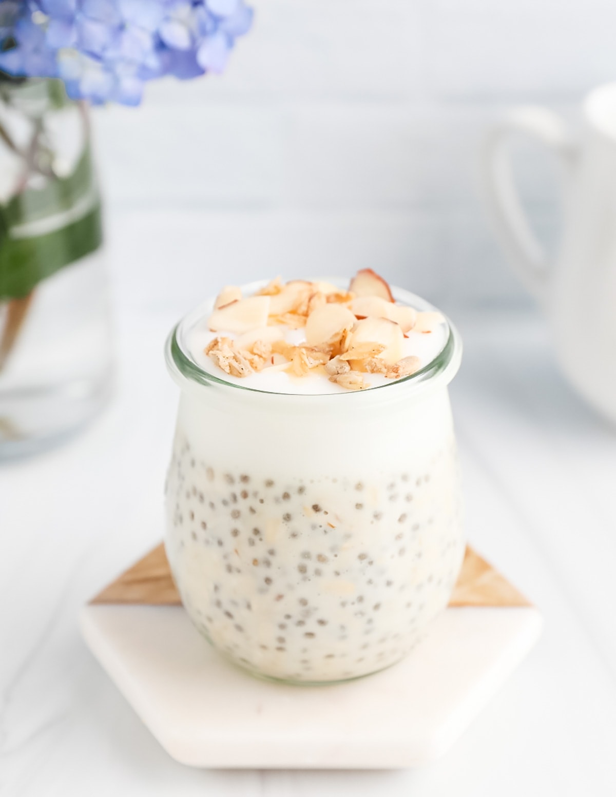 Overnight oats and yogurt in a clear cup. They are garnished with nuts and granola.