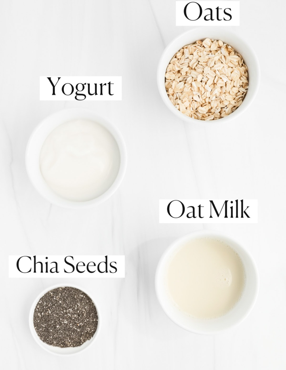 Labeled ingredients in small white bowls including: oats, yogurt, oat milk, and chia seeds.