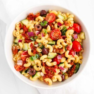 A veggie-filled pasta salad in a white bowl.