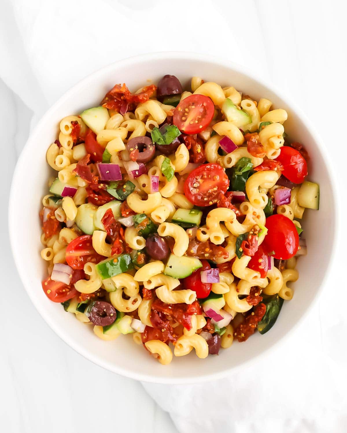An overhead image of pasta salad in a white bowl.