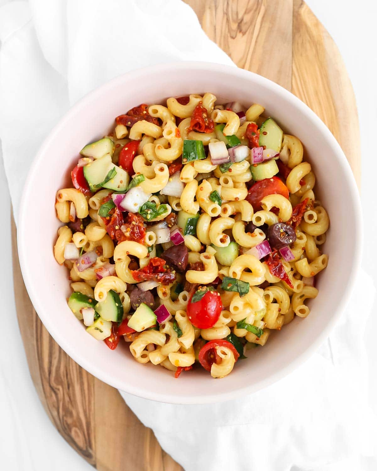 A pink bowl filled with a homemade pasta salad.