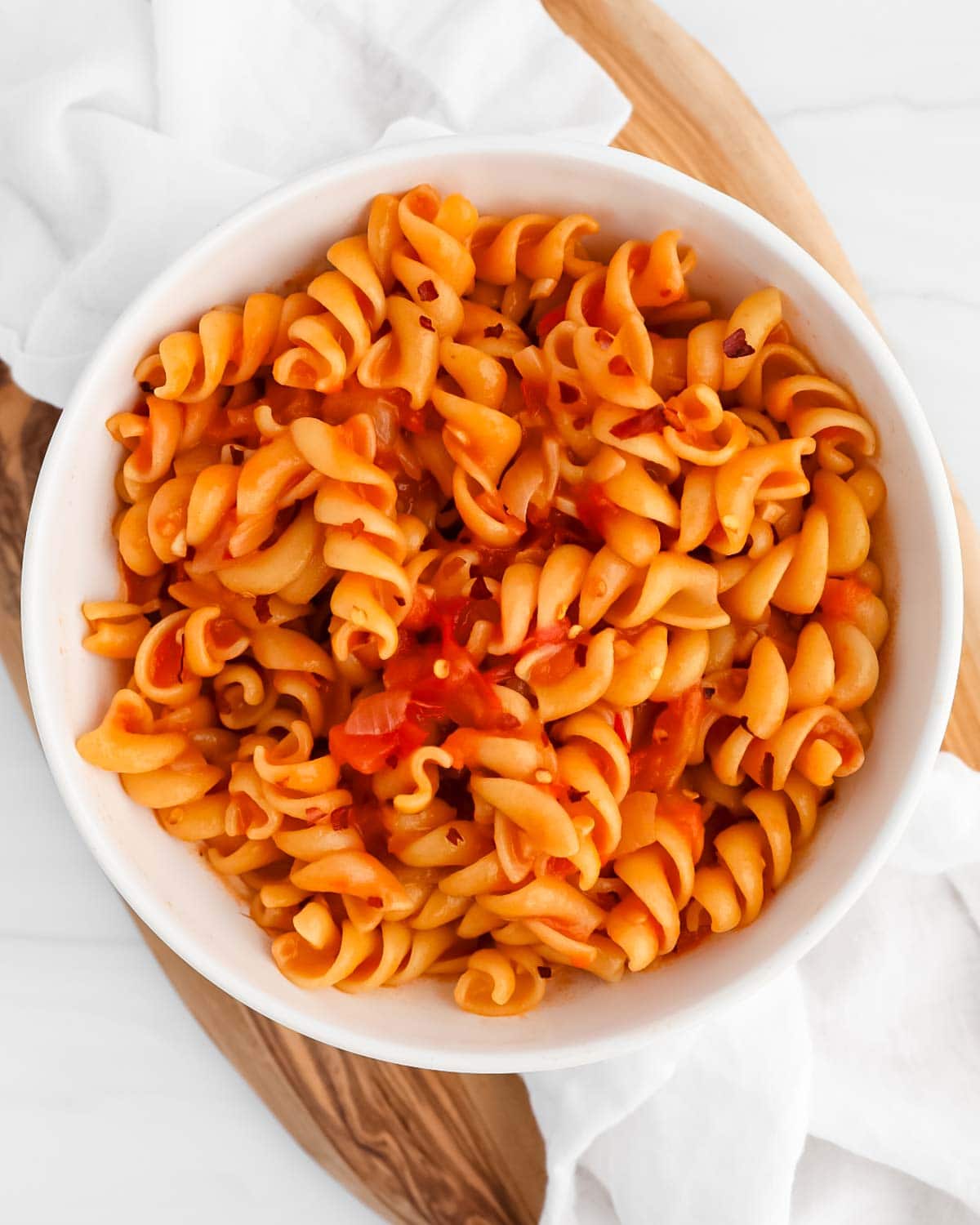Pasta in a red sauce inside a white bowl.