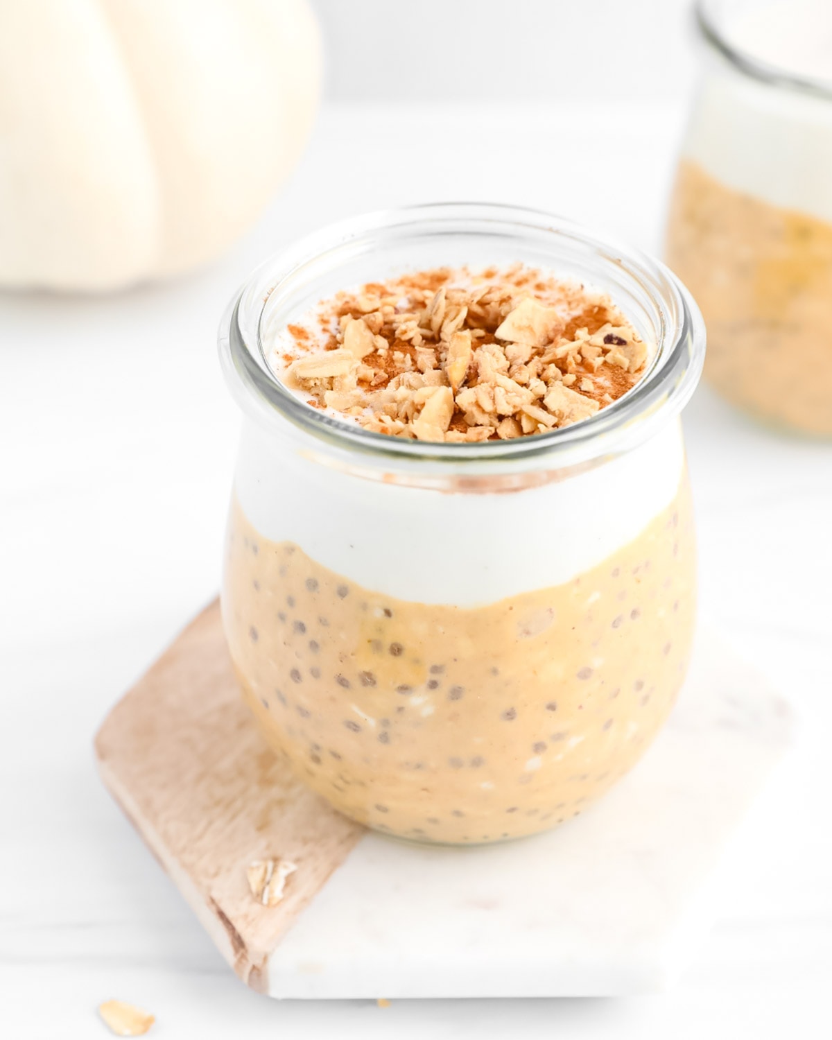 A clear glass filled with overnight oats, vanilla, and granola.