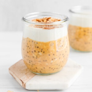 Pumpkin overnight oats in a glass jar topped with a layer of vanilla yogurt and granola.