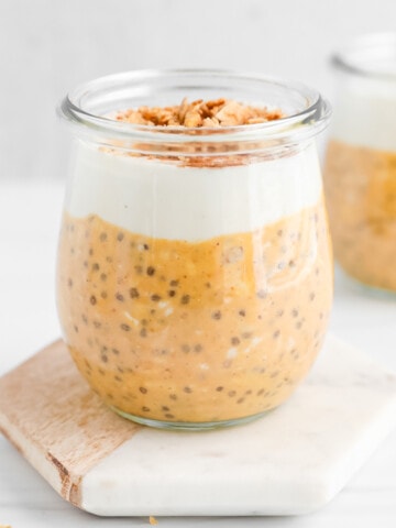 Pumpkin overnight oats in a glass jar topped with a layer of vanilla yogurt and granola.