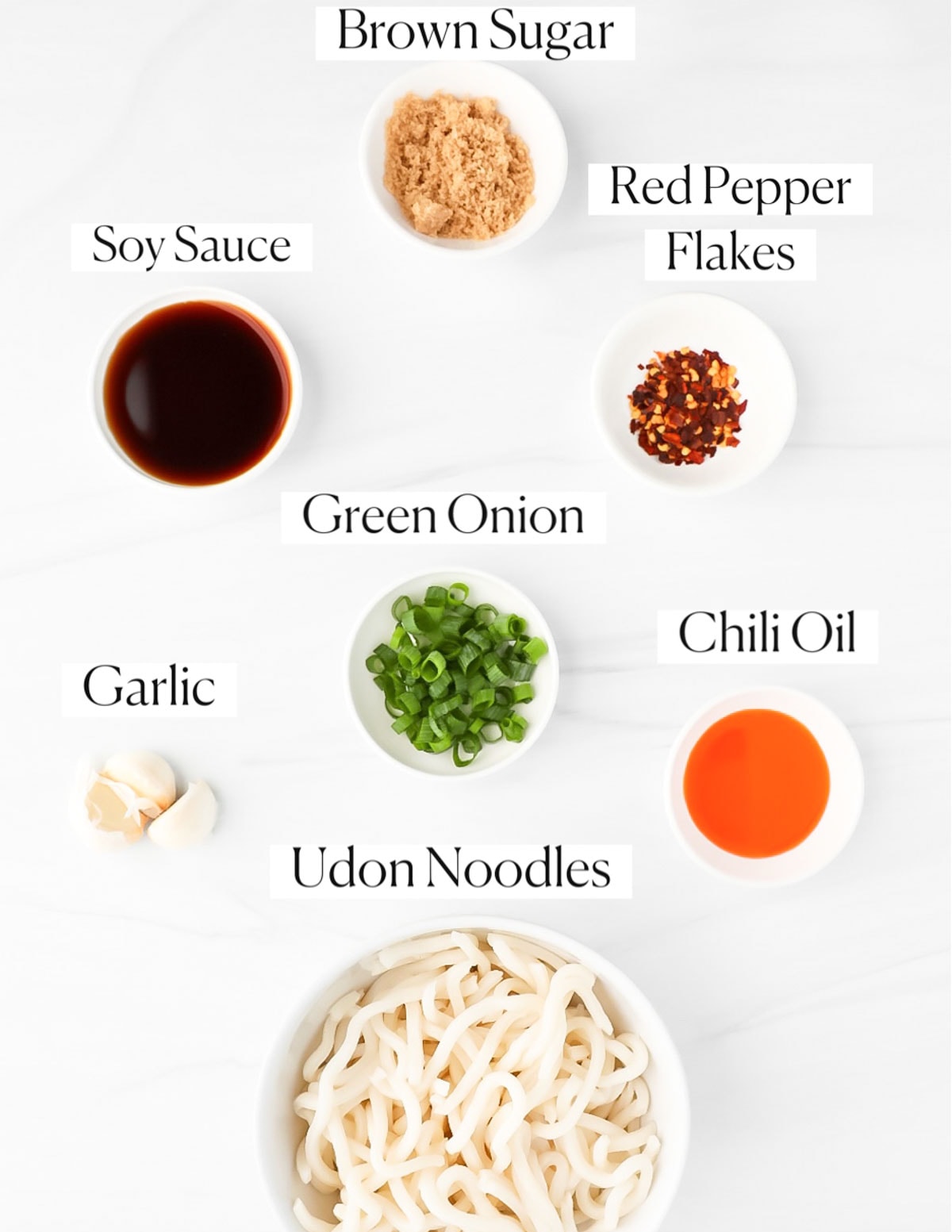 Labeled ingredients in small white bowls including: brown sugar, red pepper flakes, soy sauce, green onion, chili oil, garlic, and udon noodles,
