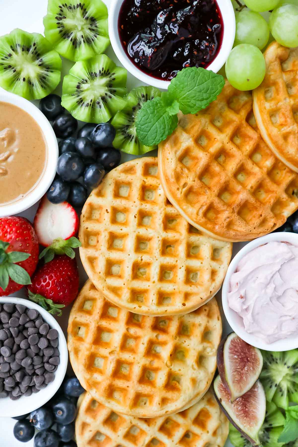 Waffles, grapes, kiwi, mint, figs, strawberries, blueberries, chocolate chips, cream cheese, peanut butter, and jelly.