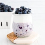 Blueberry and chia seed overnight oats in a clear glass jar with a layer of fresh blueberries and vanilla yogurt on top.