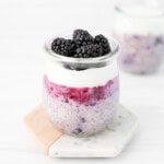 Blackberry chia seed oats in a jar with layers of jelly, yogurt, and fresh berries on top.